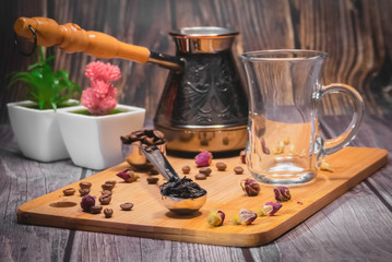 Measuring spoon for tea and coffee with coffee beans and dry tea leaves on a wooden plate.