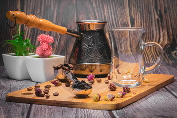 Measuring spoon for tea and coffee with coffee beans and dry tea leaves on a wooden plate.