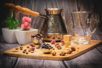 Measuring spoon for tea and coffee with coffee beans and dry tea leaves on a wooden plate.