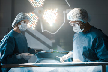 surgeon and nurse in uniforms and medical caps doing operation