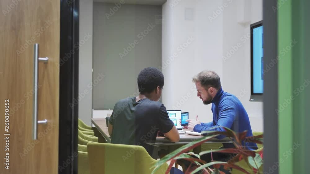 Wall mural camera entering meeting room where web designer presenting manager website templates on laptop, smar