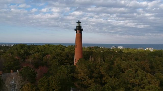 Aerial view of a red brick lighthouse with beach houses on the horizon. Currituck lighthouse, also called Currituck Beach Light, in the Outer Banks of North Carolina.