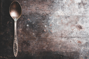 Old metal spoon on the rustic background. Selective focus.