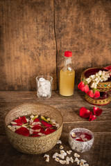 Red rose, Jasmine and popped rice on the calm water surface placed on the wood table Ready for pour water on the hands of revered elders and ask for blessing.
