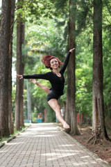 Happy redhead smiling girl dancing in a green park on Brazil in a summer day