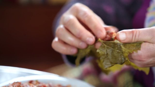 The woman is making  stuffed vine leaves