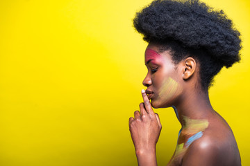 Side view of african american girl with body art on yellow