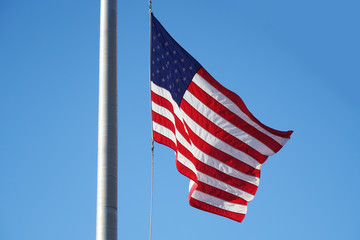 waving USA flag on pole against blue sky