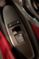 Window controlling button on the door console, black leather red lether, close-up. Сar interior details.