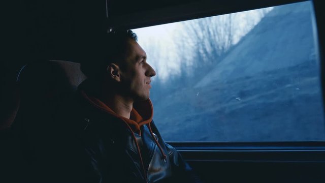 Happy Man is Looking by the Window at Sunset during Traveling by Train