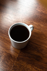 Black coffee in white cups by hand on wooden floors and coffee beans