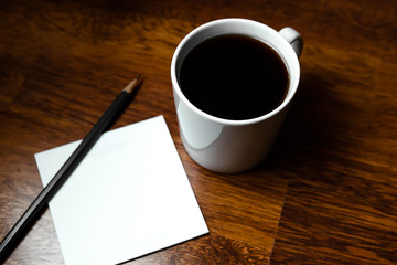 Black coffee in white cups by hand on wooden floors and coffee beans