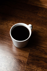 Black coffee in white cups by hand on wooden floors and coffee beans
