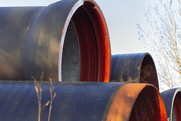 Large diameter metal pipes for water supply lie on storage areas under a open sky