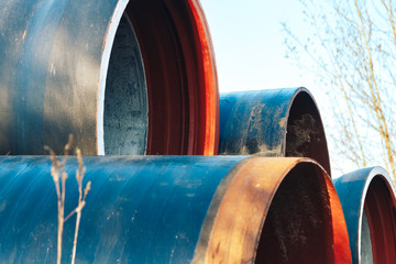 Large diameter metal pipes for water supply lie on storage areas under a open sky