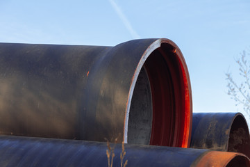 Large diameter metal pipes for water supply lie on storage areas under a open sky