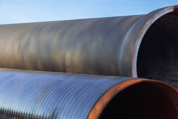 Large diameter metal pipes for water supply lie on storage areas under a open sky