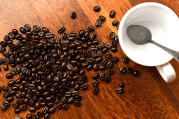 Black coffee in white cups by hand on wooden floors and coffee beans