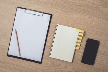 Workspace with diary or notebook and smart phone, clipboard, pencil, sticky notes on wooden background