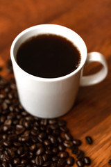 Fototapeta premium Black coffee in white cups by hand on wooden floors and coffee beans