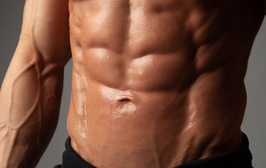 Fototapeta na wymiar Male abdominal muscles closeup with sweat drops after exercise