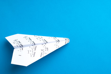 Paper jet /paper airplane made of a music score. Music score paper plane on blue.