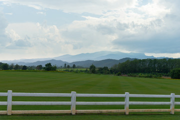 Fototapeta na wymiar White fence, grassland and mountains.
