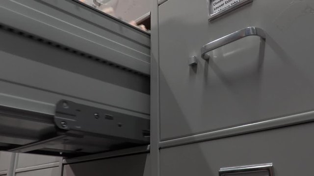 Office Worker Closing a File Cabinet in a File Storage Room.