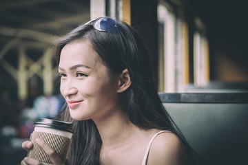 Asian woman traveler has drinking coffee in the train with happiness at Hua Lamphong station at Bangkok, Thailand.