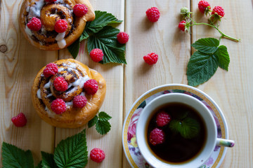 bun with raspberry berries against wooden background. cup of tea with berries.