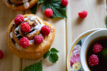 bun with raspberry berries against wooden background. cup of tea with berries.