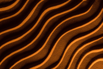 top view of textured sand with waves and orange color filter