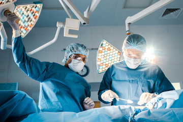 nurse and surgeon in uniforms and medical masks talking in operating room