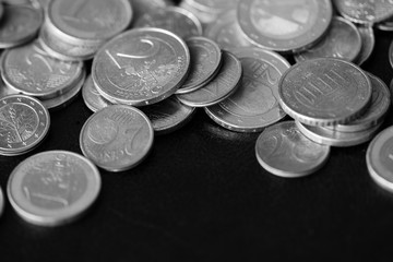 Euro coins scattered on a dark background close up. Black and white