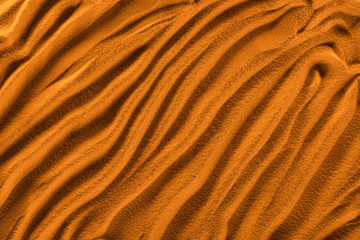top view of textured sand with waves and orange color filter
