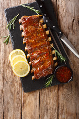 Delicious spicy grilled pork ribs with chilli sauce and lemon closeup on a slate. Vertical top view