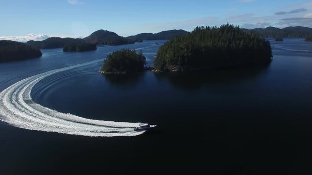 Aerial: White Motorboat Moving Across Large Blue Lake in Mackenzie Sound, British Columbia