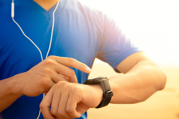 young Man running on beach and checking Heart Rate Monitor On watch