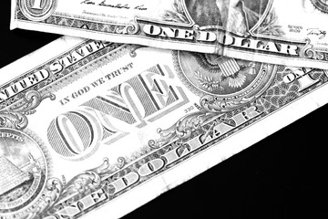Two one dollar bills on a dark background close up in monochrome