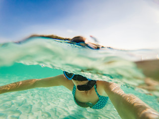 woman taking an underwater selfie while snorkeling in crystal clear tropical water