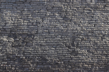 wall of an old crumbling grey stone blocks