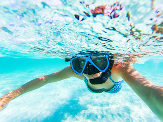 woman taking an underwater selfie while snorkeling in crystal clear tropical water