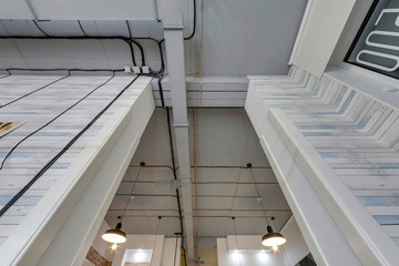 wires, ventilation, detectors and lamp on grey ceiling