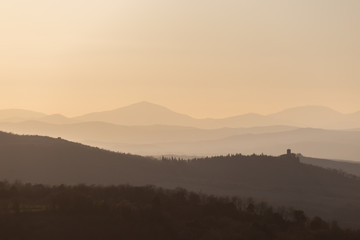Beautiful view of Tuscany hills at sunset, with mist and warm colors