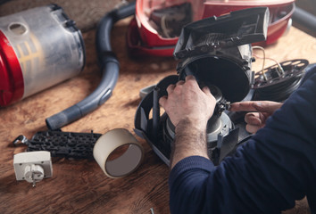 Man repairs of vacuum cleaner. Repairing - obrazy, fototapety, plakaty