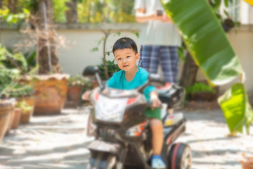 Little Asian boy riding bicycle toy inthe house with happy face