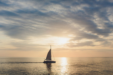 Naklejka na ściany i meble Yacht sailing against sunset. Holiday lifestyle landscape with skyline sailboat and two seagull. Yachting tourism - maritime evening walk. Romantic trip on luxury yacht during the sea sunset.