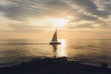 Fototapeta na wymiar Yacht sailing against sunset. Holiday lifestyle landscape with skyline sailboat and two seagull. Yachting tourism - maritime evening walk. Romantic trip on luxury yacht during the sea sunset.