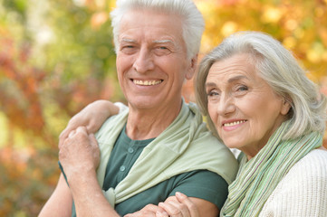 Happy senior couple in autumn park hugging 