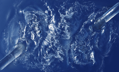 Two Large Water Jets splashing in a blue Liquid with foam and many waves